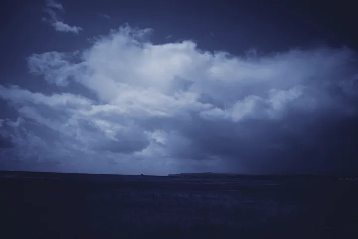 A moody landscape with dramatic clouds above a dark and foreboding landscape