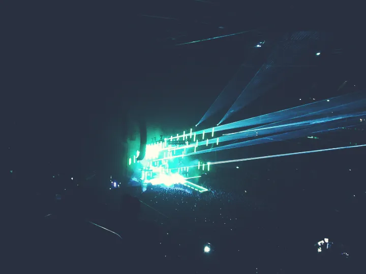 Lasers and light beams emitting from a stage in a dark arena